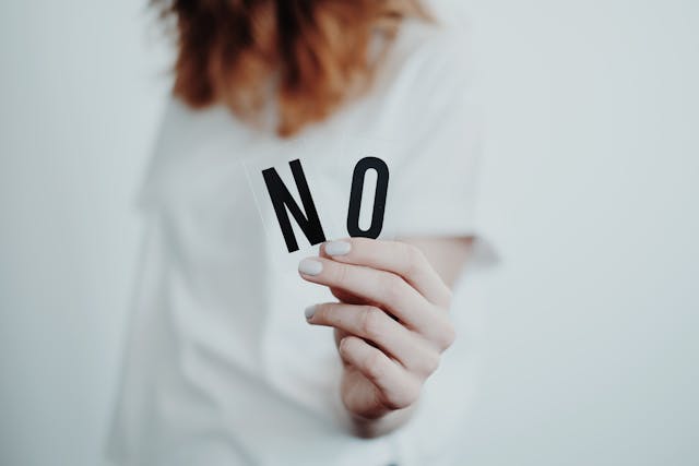 NOという文字を手にしてる女性