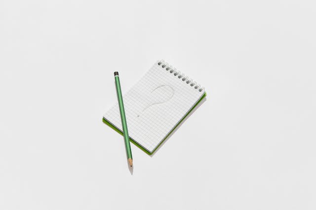 クエスチョンマークが書かれたメモと鉛筆