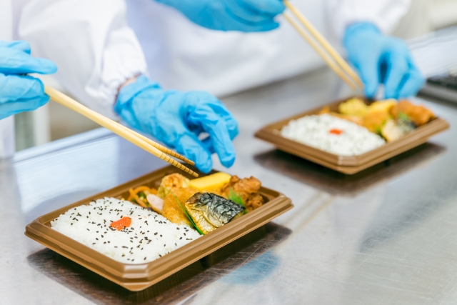 お弁当の製造工場無いので盛り付けをしている場面