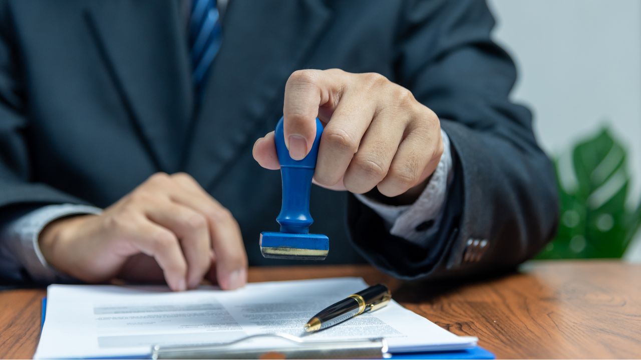 ビザの申請書類に承認印を押している場面