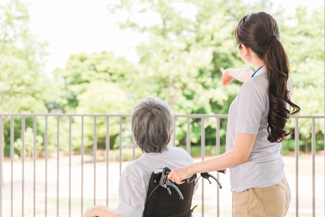 散歩する車椅子に乗った高齢者と介護士