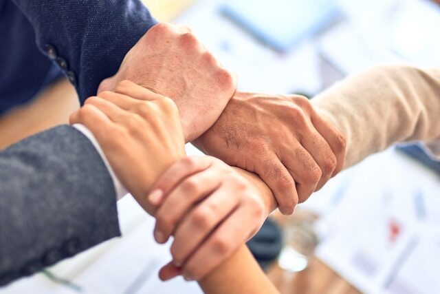 お互いの手首を握りチームワークの結束を表した場面
