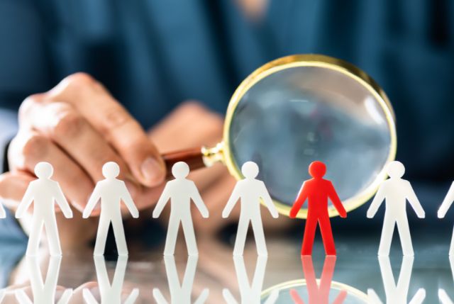 人材紹介をイメージした人型の人形を虫眼鏡で調べている人