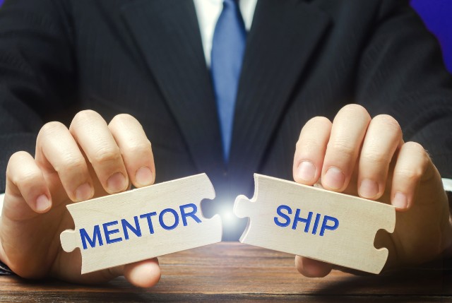 MENTORSHIPと書かれたパズルのピースを合わせているビジネスマン