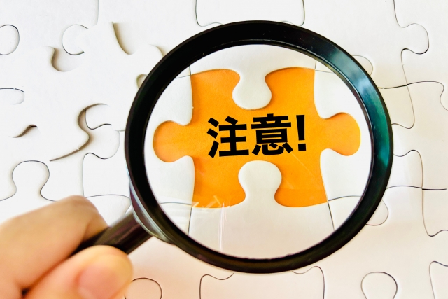 注意するところを発見している虫眼鏡と注意と書かれたパズルのピース