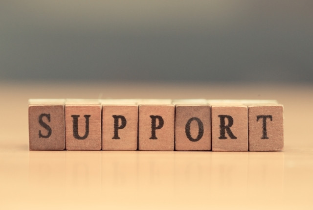木製ブロックに印字された文字が並び、SUPPORTと綴られている様子