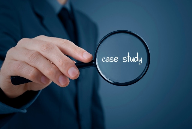 スーツを着たビジネスマンが虫眼鏡で“case study”という文字を拡大している様子。外国人正社員の求人・採用方法に関する企業事例やケーススタディを表現