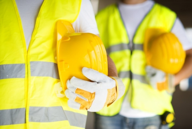 建設現場で黄色い安全ベストとヘルメットを持つ労働者たち。外国人労働者の雇用をテーマにした企業向け最新ガイド記事のイメージ