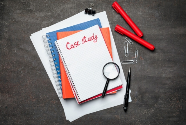 ノートにCase studyと書かれたメモ帳と文房具。ビジネスでの外国人受け入れの事例研究を示すイメージ