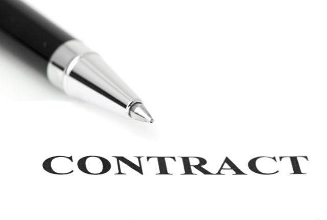 契約書の「CONTRACT」文字とペンのクローズアップ。特定技能外国人の雇用契約や労働条件確認のイメージ。