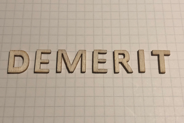 木製のアルファベットで並べられた“DEMERIT”の文字。外国人雇用のデメリット解説記事用のイメージ