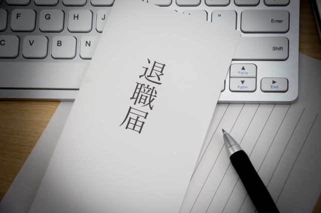 退職届とペンがキーボードの上に置かれ、人材紹介で採用した社員の早期退職を示すイメージ。