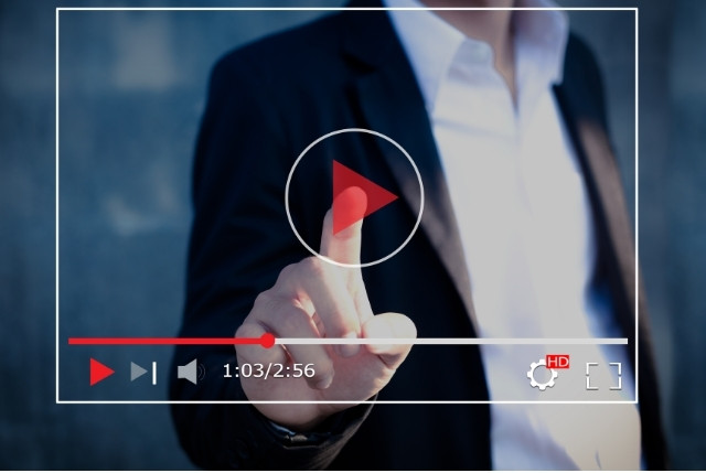 動画再生ボタンを押す男性の手元。生活オリエンテーションで外国人向けの学習動画を視聴するイメージ。