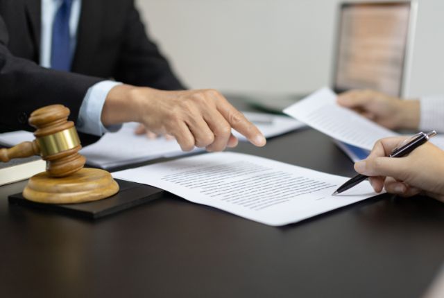 契約書に署名するビジネスシーン。外国人労働者の雇用契約や法的手続きの違反に関する打ち合わせを示すイメージ。