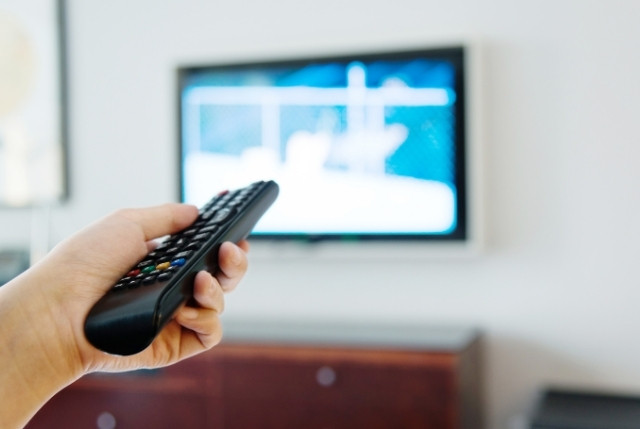 テレビの前でリモコンを操作する手元の様子。生活オリエンテーションで騒音などについて学ぶ場面。
